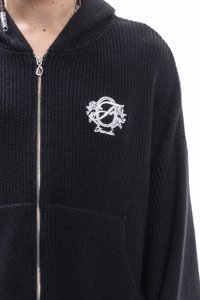 Black zippered hoodie made of textured knit fabric. Features a front pocket and embroidered logo on the left chest area.