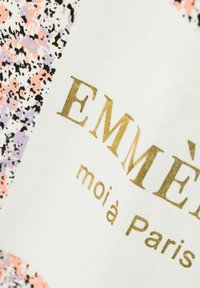 Multifarvet stof med sorte, lyserøde og lilla sprøjt. Har guldtrykt tekst: "EMMÈ" og "moià Paris" på en hvid baggrund.