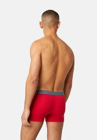 Red boxer shorts with a gray waistband. The fabric appears smooth with a fitted design, showcasing a solid color and minimal detailing.