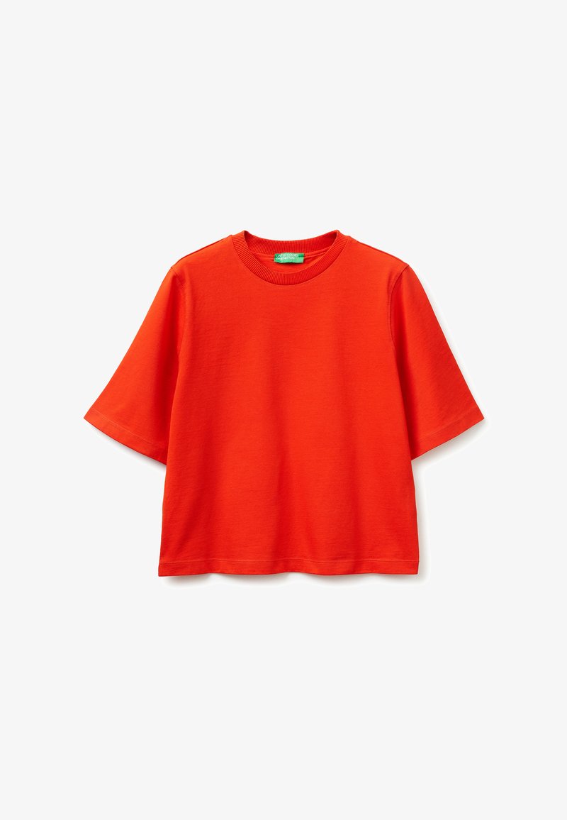 T-shirt à manches courtes de couleur rouge vif, col rond, coupe décontractée avec une étiquette verte à l'intérieur du col, présenté sur un fond blanc.