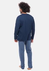 Laivastonsininen pitkähihaise paita ja sinivalkoiset ruudulliset yöhaalarihousut. Pehmeä puuvillakangas, jossa on rento leikkaus ja yksinkertainen muotoilu.