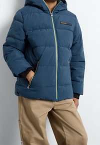 Blaues auffälliges Jacket mit Kapuze, ausgestattet mit gelben Akzenten, einem Reißverschluss vorne, elastischen Bündchen und seitlichen Taschen mit einer glatten Textur.