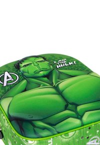 Mochila verde con un diseño de un personaje de dibujos animados musculoso, con el texto "¡SOY EL HULK!" en blanco. Superficie texturizada con colores vibrantes.