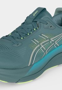 Μπλε-πράσινο παπούτσι τρεξίματος Asics με επάνω μέρος από διχτυωτό υλικό, κλείσιμο με κορδόνια, επενδυμένη σόλα και λογότυπο της μάρκας στο πλάι.