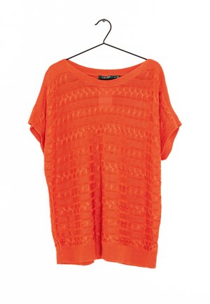 Jasnopomarańczowy krótki sweter z dzianiny z teksturowanymi poziomymi wzorami, wiszący na czarnym wieszaku na białym tle.