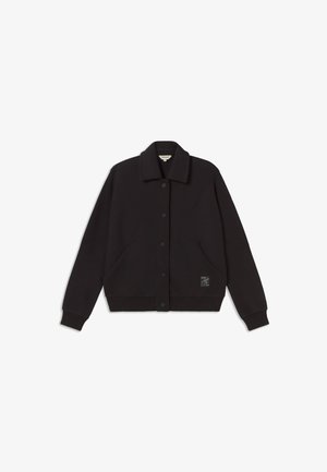 Veste noire avec une fermeture à boutons, col pointu, deux poches latérales et poignets côtelés. Présente un tissu texturé et un patch logo.