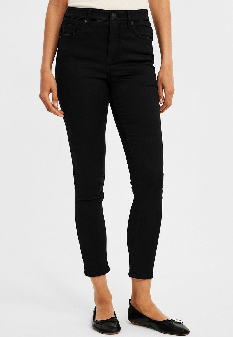 Korkeavyötäröiset mustat farkut, joissa on slim fit -malli. Ominaisuuksiin kuuluvat viisi taskua, nappisuljenta ja hillityt ompeluyksityiskohdat. Miellyttävä, sileä pinta.