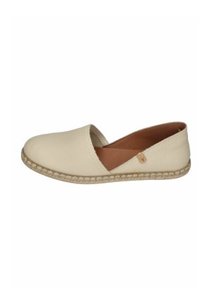 Cremfarbener Slip-On-Flachschuh mit strukturierter Sohle und offenem seitlichem Detail, versehen mit einem kleinen Lederetikett am äußeren Rand.