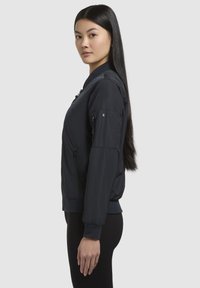 Giacca bomber navy in nylon liscio con polsini e orlo a costine, dotata di zip frontale e tasche decorative sulle maniche.