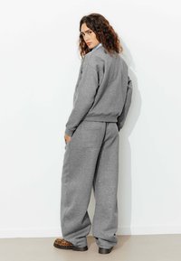 Sweatshirt gris et pantalon de jogging large assorti, fabriqués en tissu doux, avec une coupe décontractée, des poches avant et des sabots en imprimé léopard.