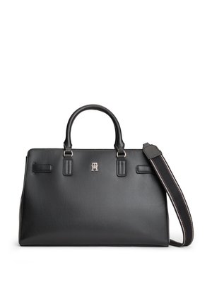 Schwarze Lederhandtasche mit zwei Griffen, einem abnehmbaren schwarzen Riemen mit weißen Nähten und einem kleinen silbernen Logo vorne in der Mitte.