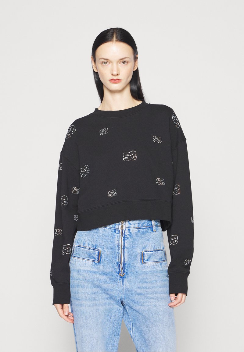 Schwarzer, kurzer Sweatshirt mit Rundhalsausschnitt, verziert mit einem verstreuten Design aus Strasssteinen. Kombiniert mit hellblauen, hochtaillierten Jeans.