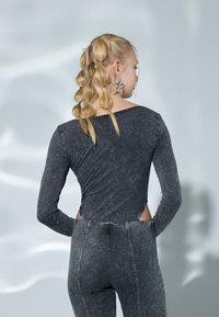 Gray long-sleeve bodysuit with cut-out sides, paired with matching gray high-waisted pants. Material shows a faded, textured appearance.
