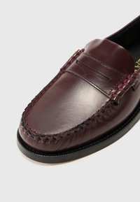 Loafer din piele burgundă, cu un design cusut, textură netedă, cusături de accent negre și vârf rotunjit.