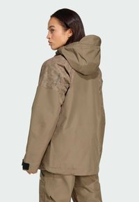 Brown waterproof jacket with a textured tan hood, featuring a logo on the shoulder and Velcro cuffs. Simple, functional design.
