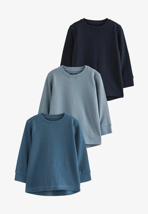 Drei langärmelige Hemden in verschiedenen Blautönen. Gerippte Textur, runde Ausschnitte und leicht abgerundete Säume.