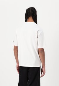 Hvid kortærmet t-shirt med rund hals, lavet af bomuld. Har en afslappet pasform og et enkelt design, uden synlige mønstre eller grafik.