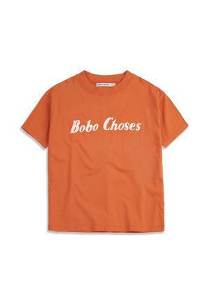 T-shirt orange à manches courtes en coton avec le texte blanc « Bobo Choses » imprimé sur la poitrine, encolure ronde et étiquette de marque visible à l'intérieur du col.