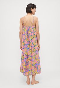 Floral maxi dress with thin straps, featuring a purple base adorned with yellow and pink flowers. Flowy fabric and a relaxed silhouette.