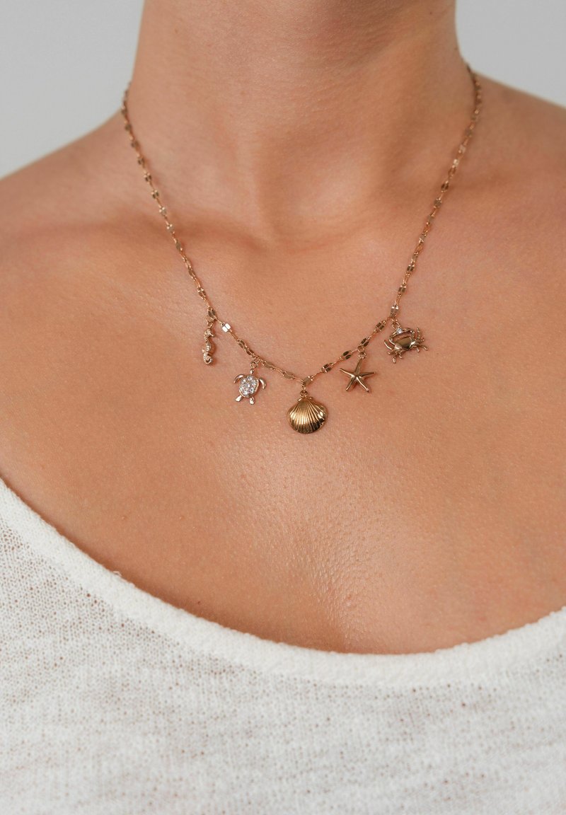 Halskette in Goldoptik mit mehreren meeresbezogenen Charms: ein Seepferdchen, eine Schildkröte, eine Jakobsmuschel, ein Seestern und eine Krabbe an einer filigranen Kette.