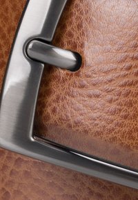 Brązowa skórzana tekstura z metalowym zapięciem w kolorze srebrnym, o prostokątnym kształcie i polerowanym wykończeniu, przymocowana do skórznego paska.