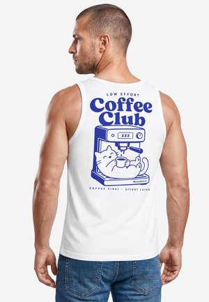 Man wearing white tank top with blue graphic of relaxed cat holding coffee cup inside coffee machine and text "Coffee Club" on back.