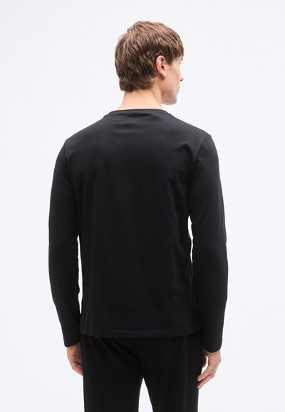 Svart langermet T-skjorte laget av myk bomull. Har en klassisk rund hals og en rett kant, med en jevn, uutsmykket tekstur.