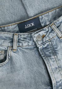 Šviesiai mėlynos džinsinės kelnės su įprastu kirpimu, sagčių uždarymu, geltonomis siūlėmis ir pažymėjimu su užrašu "JJXX."