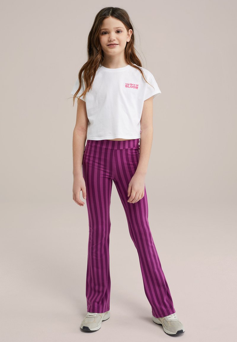 Valge lühikeste varrukatega T-särk roosa tekstiga ja lillaga triibulised laiendatud retuusid. Retuusidel on vertikaalsed triibud ja sile tekstuur.