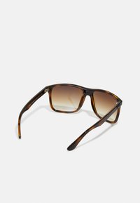Ochelari de soare cu rame dreptunghiulare în culori de țestoasă, lentile cu gradient și brațe groase, având un branding subtil pe lateral.