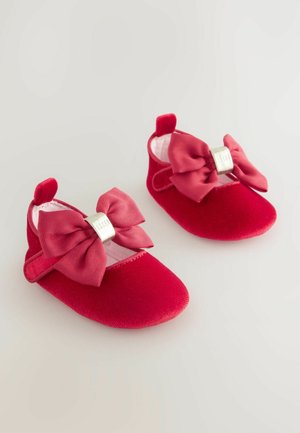 Rote Samtbabyschuhe mit weicher Textur, versehen mit übergroßen rosa Schleifen und silbernem Zubehör für einen sicheren Verschluss.