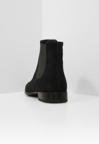 Schwarze Wildleder Chelsea-Stiefel mit seitlichen elastischen Einsätzen, einer abgerundeten Spitze und einem niedrigen, flachen Gummihighheel. Glatte Textur mit matter Oberfläche.