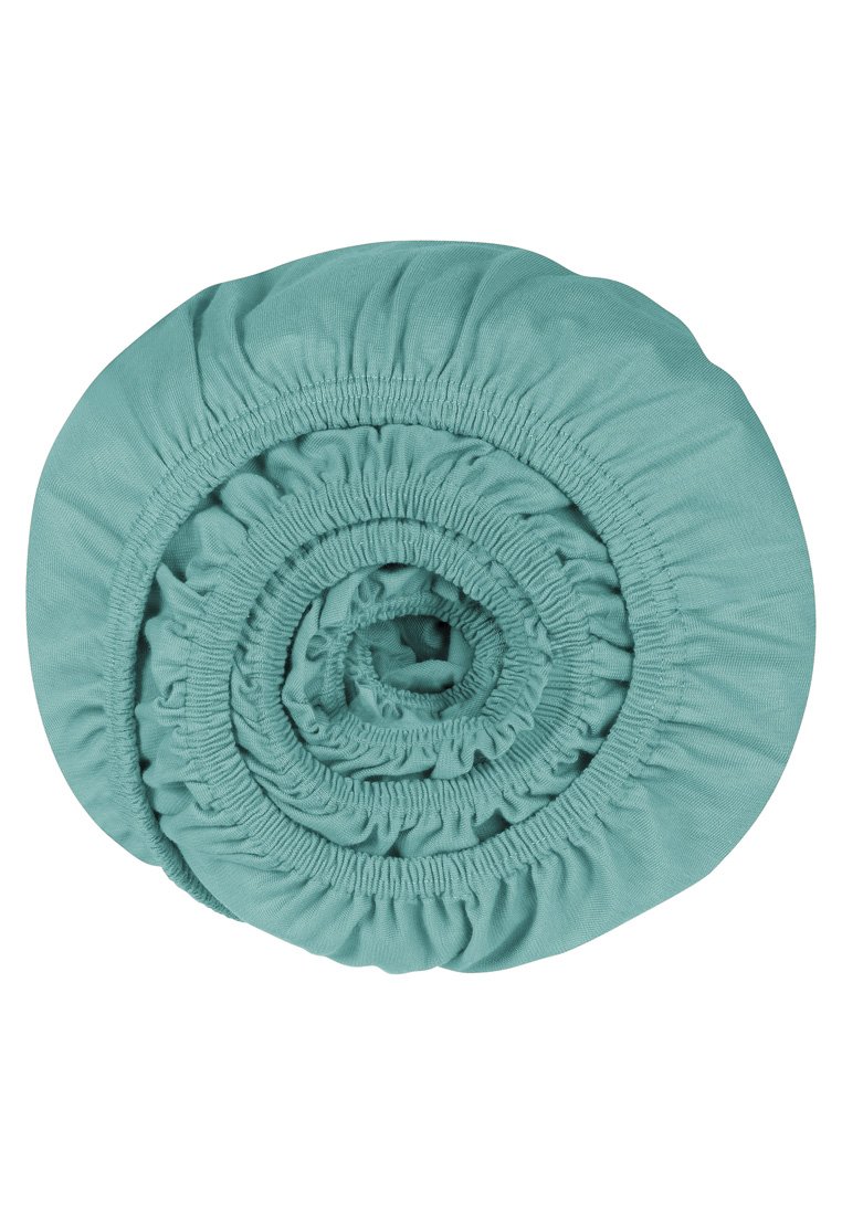 Zielona bawełniana okrągła torba na przechowywanie, ciasno zwinięta, z elastycznymi, marszczonymi krawędziami i gładką teksturą na całej powierzchni.