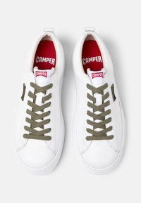 Sneakers bianche in pelle con lacci verdi, punta tonda e colletto imbottito. Fodera interna rossa con logo "CAMPER" bianco sulla linguetta. Suola leggera.