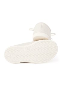 Baskets blanches à enfiler avec une semelle texturée, un bout arrondi et de petites boucles à l'arrière pour un enfilage facile. Surface lisse et design minimaliste.
