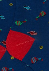 Blue socks with a red heel, featuring colorful patterns of maracas and yellow dots. Made of soft, knitted fabric.