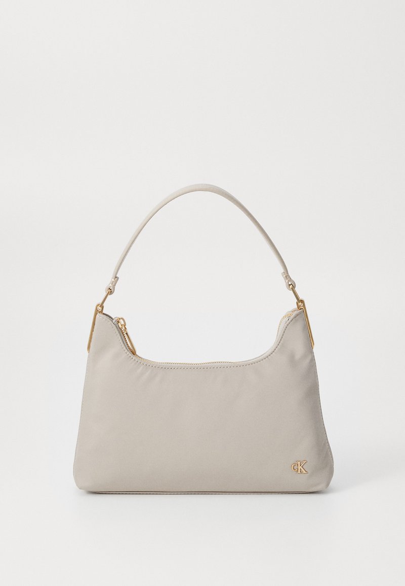 Bežinė audinio piniginė su lygiu paviršiumi ir auksiniais aksesuarais. Turi kreipiamąjį rankeną ir užtrauktuką viršuje. Subtilus logotipo detalė.