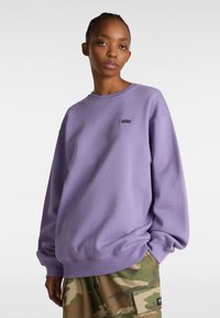 Sudadera púrpura hecha de una tela suave, con cuello redondo y un pequeño logo negro de Vans en el pecho. Ajuste relajado con mangas largas.