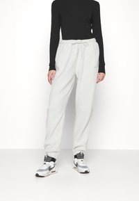 Harmaat fleece-housut, joissa on joustava vyötärö ja nyöri, kapeat lahkeet ja kaksi sivutaskua.