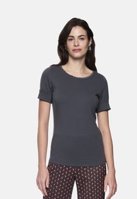 Graues T-Shirt mit kurzen Ärmeln, rundem Ausschnitt und aufgerollten Bündchen, aus weichem Stoff, kombiniert mit gemusterten Hosen mit geometrischem Design.