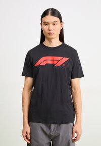 Black cotton t-shirt featuring a large red Formula 1 logo on the front. Short sleeves, crew neck, and a relaxed fit.