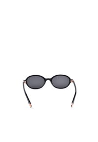 Lunettes de soleil ovales noires avec des verres foncés et des branches fines, présentées sur un fond blanc.