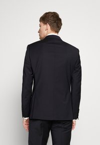 Marineblauwe blazer met gestructureerde schouders, een soepele textuur, een enkele split aan de achterkant en vier knoopaccenten op de mouwen.