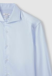 Chemise ajustée bleu clair à col pointu, devant boutonné et tissu lisse ; présente un léger éclat et ne comporte ni motifs ni accents.