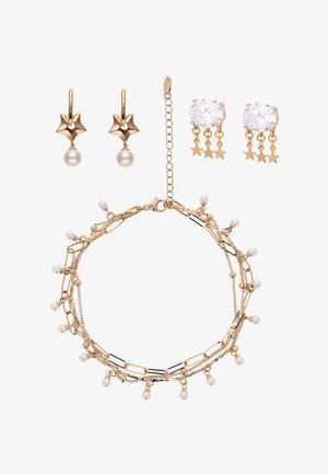 Parure de bijoux dorés comprenant des boucles d'oreilles en forme d'étoile ornées de perles, des boucles d'oreilles pendantes en forme d'étoile avec des pierres claires, et un bracelet à maillons avec des breloques perle.