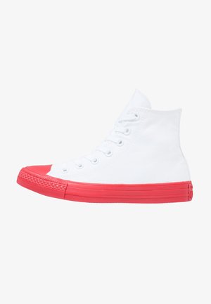 Basket montante avec dessus en toile blanche et semelle ainsi que bout en caoutchouc rouge vif, vue de côté.