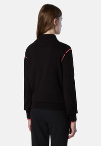 Maglione nero con colletto alto, caratterizzato da accenti a strisce rosse sulle spalle e polsini e fondo a coste. Tessuto morbido e testurizzato.