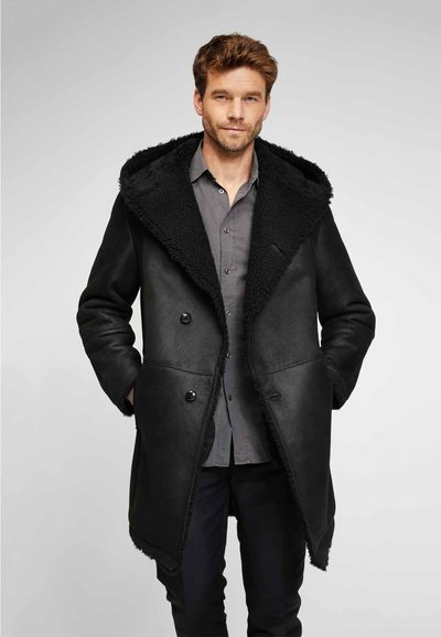 Cappotto doppiopetto nero con collare in finta pelliccia testurizzata, realizzato in morbido materiale di pelle e dotato di due tasche frontali.