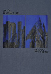 Deux panneaux noirs et bleus côte à côte montrant des gratte-ciel de la ville et un sommet de montagne, avec le texte "HALO" et "OFF DUTY GEAR".