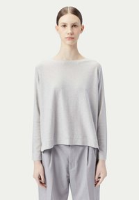 Ljusgrå, långärmad topp med bred halsringning och avslappnad passform, tillsammans med ljusgrå plisserade byxor. Mjukt tyg med subtil textur.